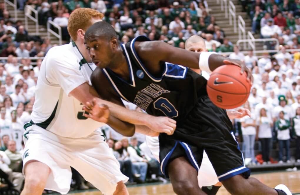 Eziukwu pushes past another player while playing baskeball during his time at GVSU